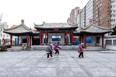 Two women walk on the streets near the red and white cement building during the day
